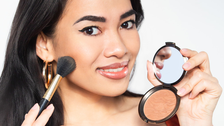 woman applying bronzer