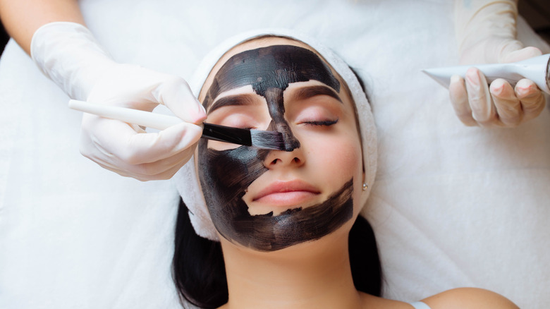 woman getting charcoal mask applied