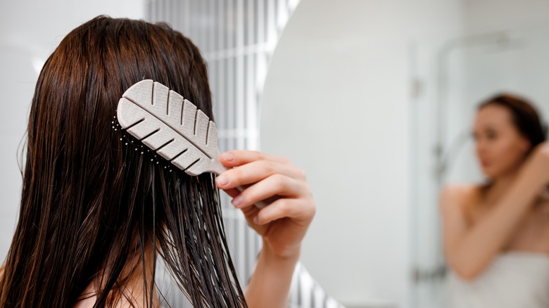 Woman brushing wet hair in mirror