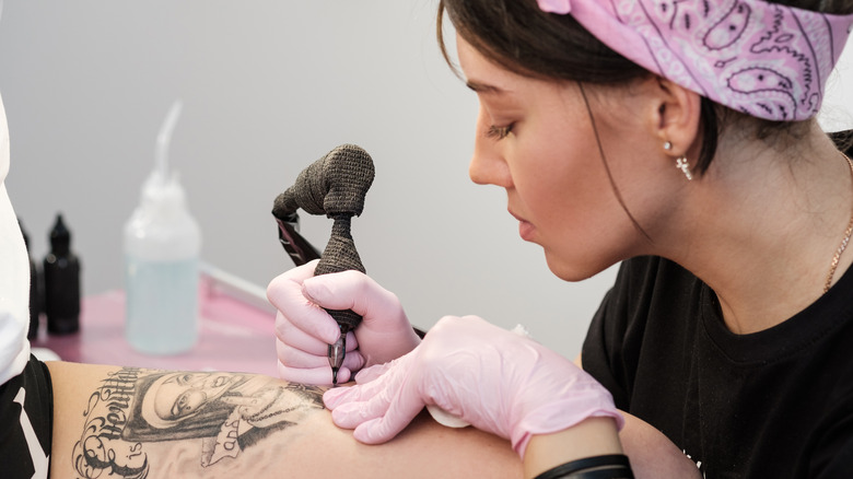 Woman doing tattoo on thigh