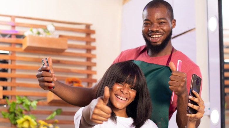 Hairstylist and client giving thumbs-up gestures