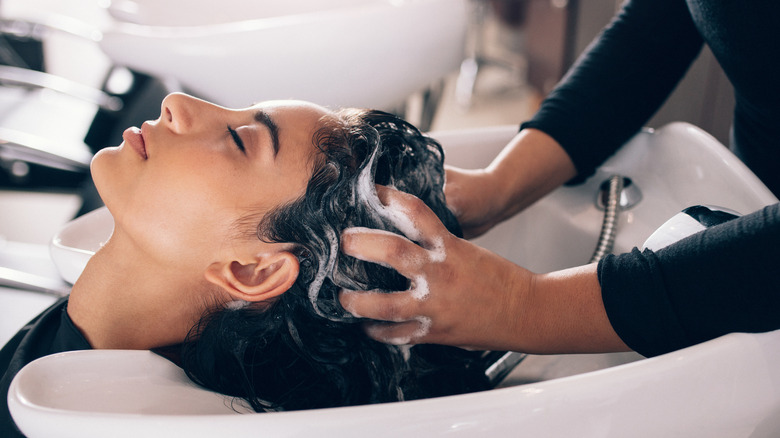 Client having head massaged in shampoo bowl