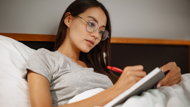 Asian woman journaling in bed