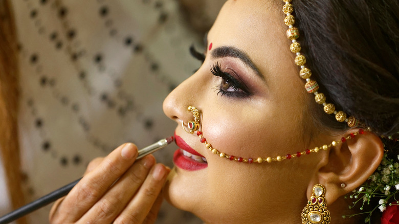 Smiling bride getting lipstick applied