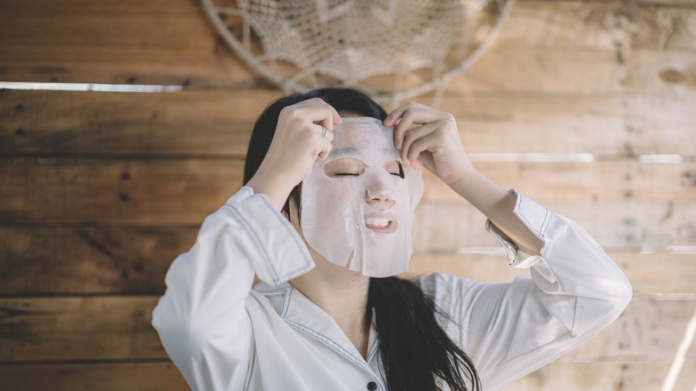 woman applying sheet mask