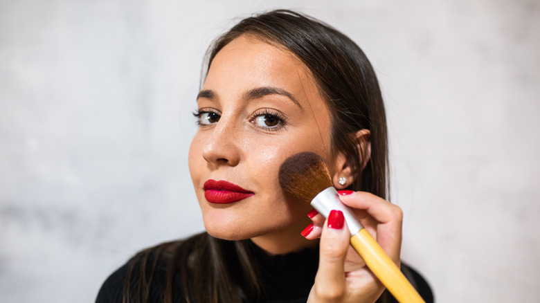 Woman applying blush in the mirror