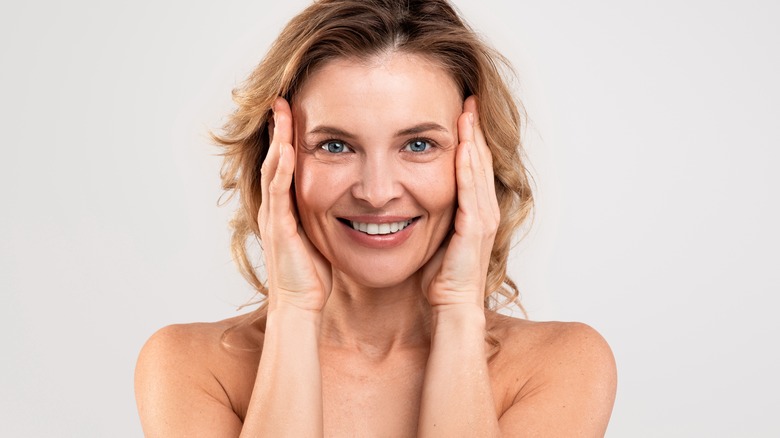 woman smiling, touching face