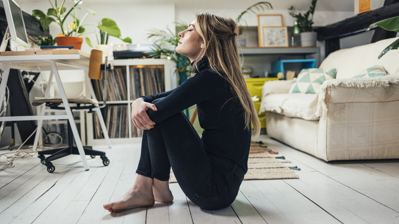 woman hugging knees inside