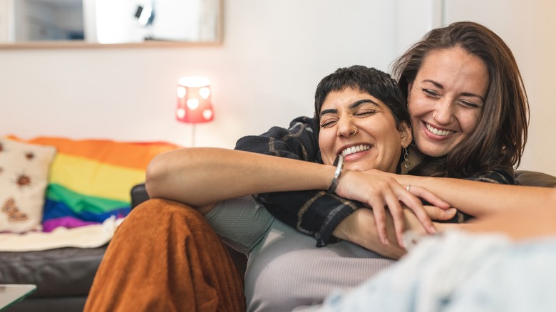 young lgbtq+ couple snuggling on couch