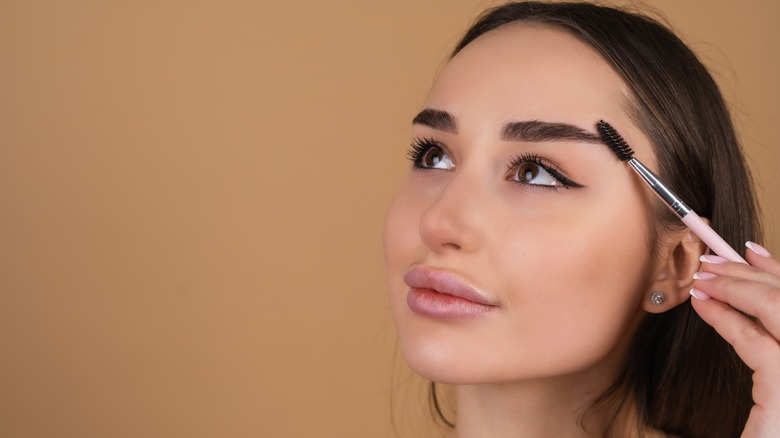 woman holding spoolie to eyebrow