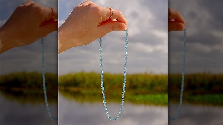 Hand holds blue beaded necklace