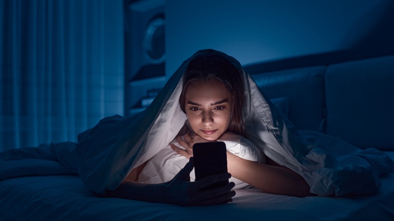 Woman on phone under covers