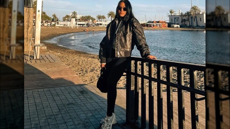 Woman in leather jacket, leggings, and sneakers