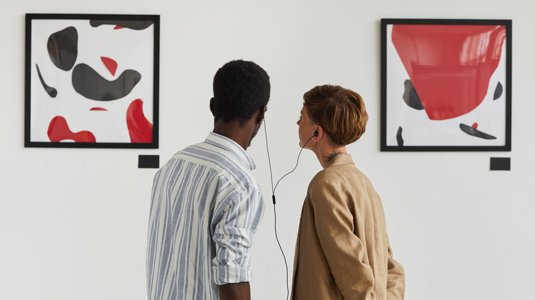 Couple sharing headphones in art gallery