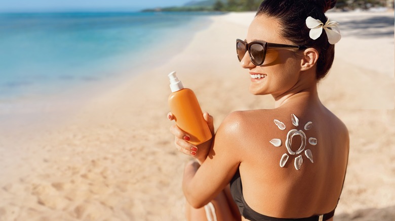 Woman applies sunscreen on beach