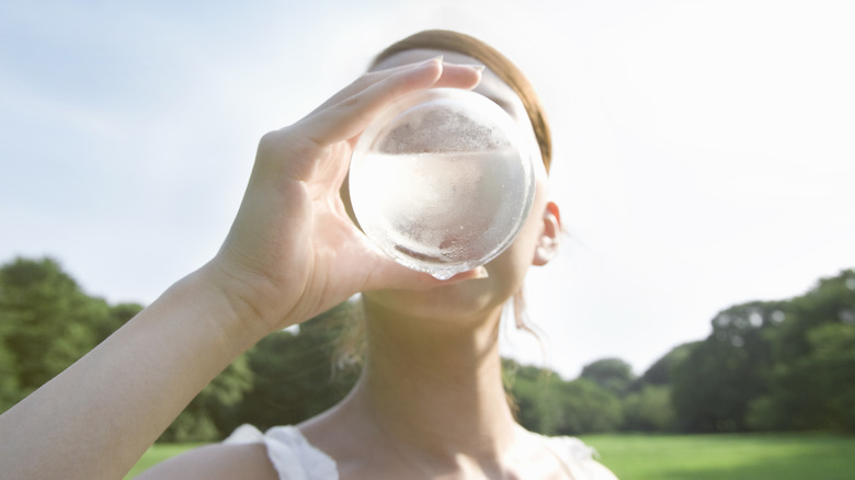 Woman drinks water outdoors