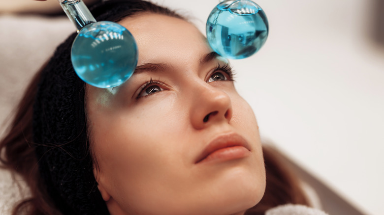 Woman using facial ice globes 