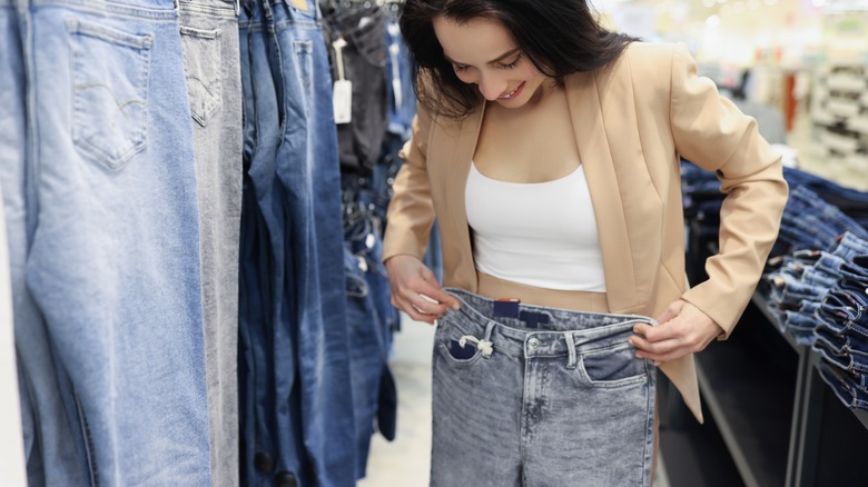 Woman holding up jeans in store