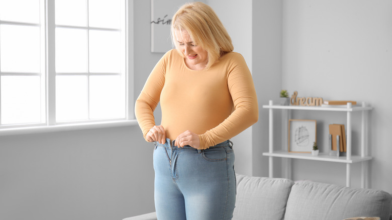 Woman struggling to zip tight jeans