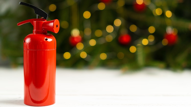 fire extinguisher with Christmas tree behind