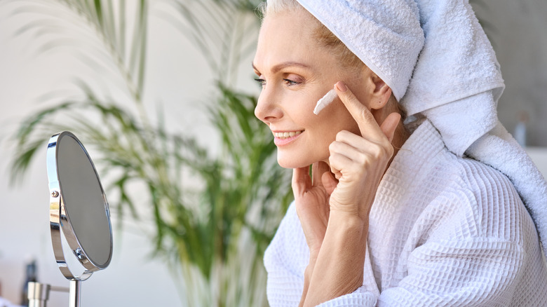 older woman applying moisturizer