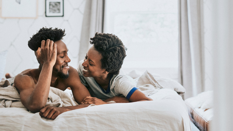 young black couple smiling in bed