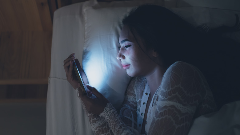 Woman uses phone in bed