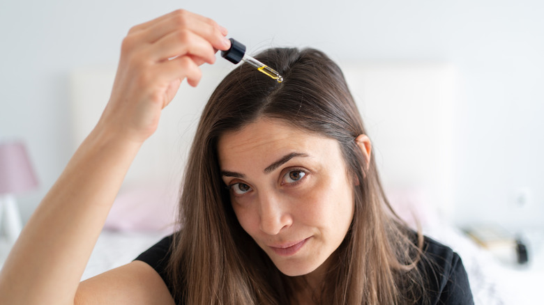 woman applying serum on scalp