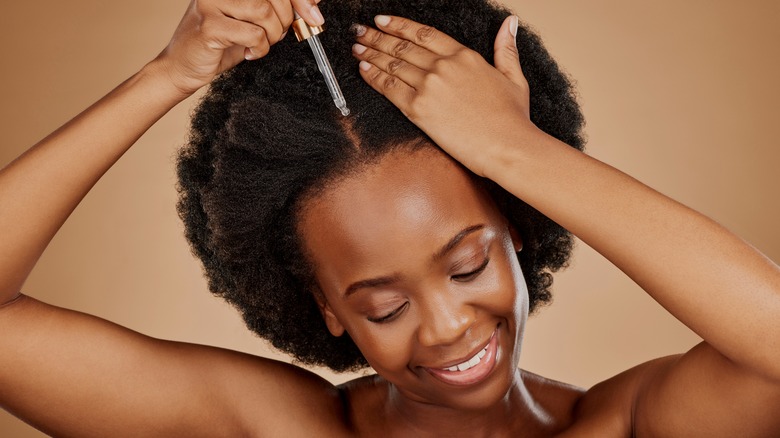 woman applying serum to scalp