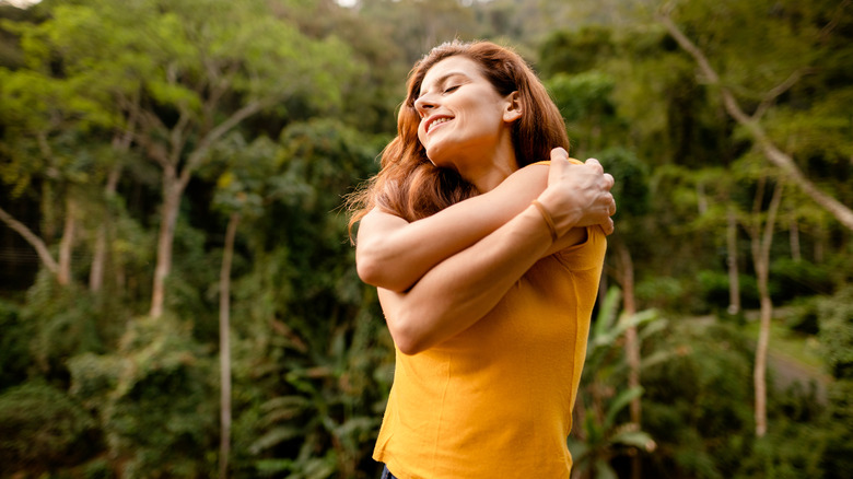 Smiling woman hugging herself