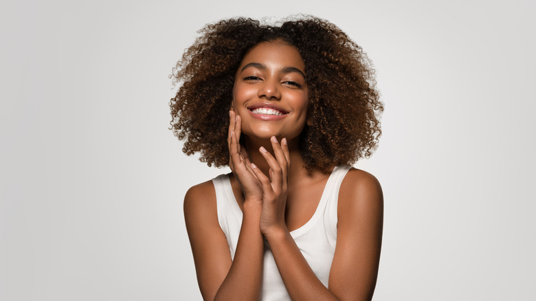 woman smiling while touching skin 