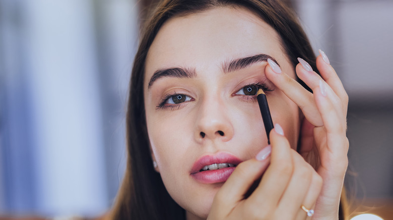 Woman applying black eyeliner