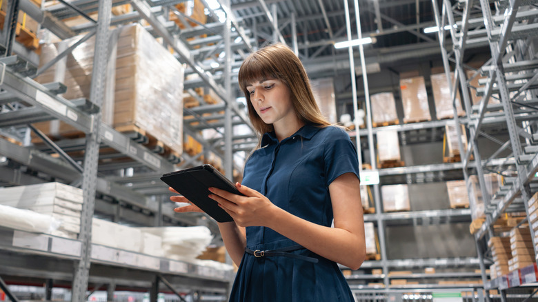 Woman using tablet amongst inventory in warehouse setting