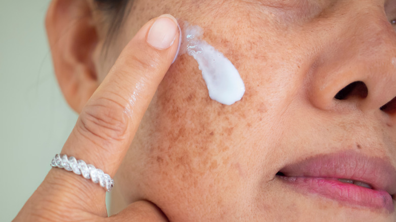 Woman applying sunscreen to face