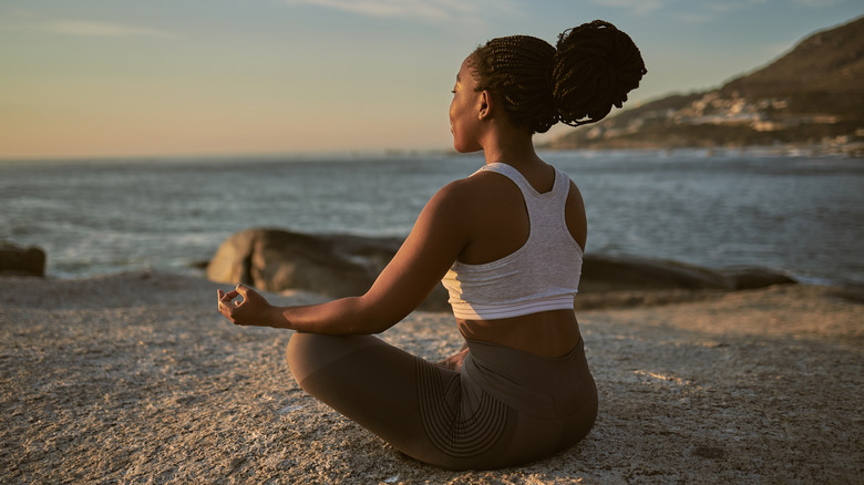 Woman does yoga by water