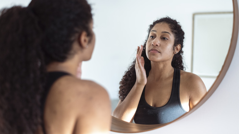 woman touching face in mirror