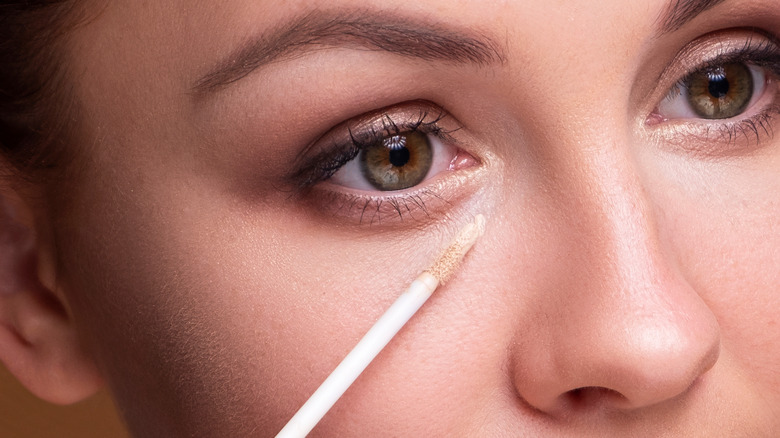 woman applying concealer under eye