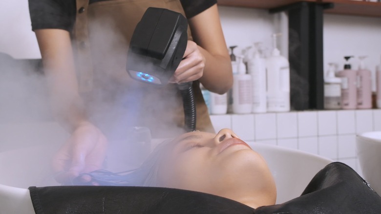 Woman getting hair steamed at salon