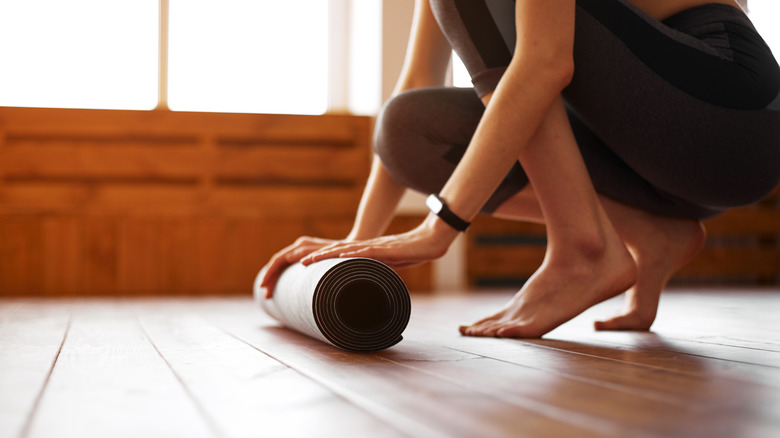 woman rolling up yoga mat