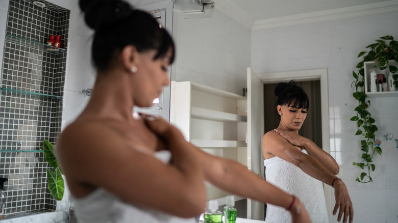 woman applying lotion after shower