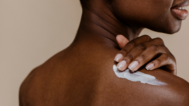 woman applying cream on back