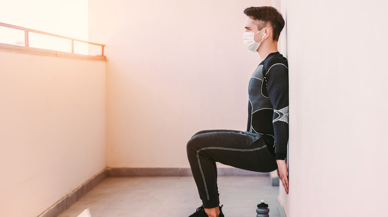 Masked man doing wall sit