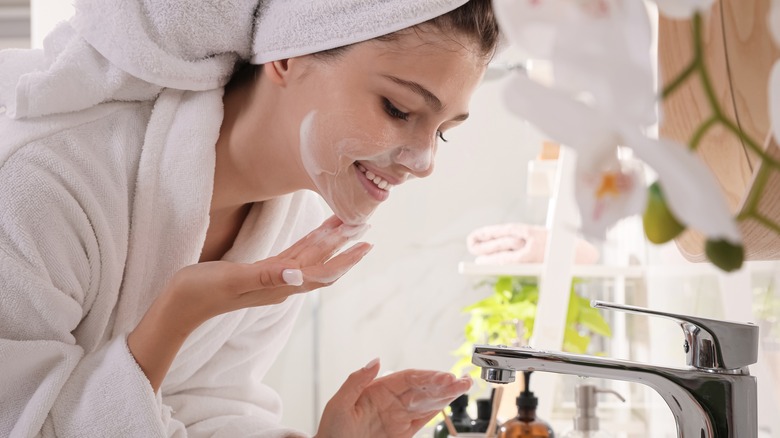 girl washing face at sink