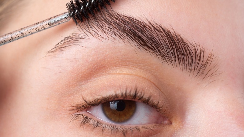 A woman brushing her eyebrows