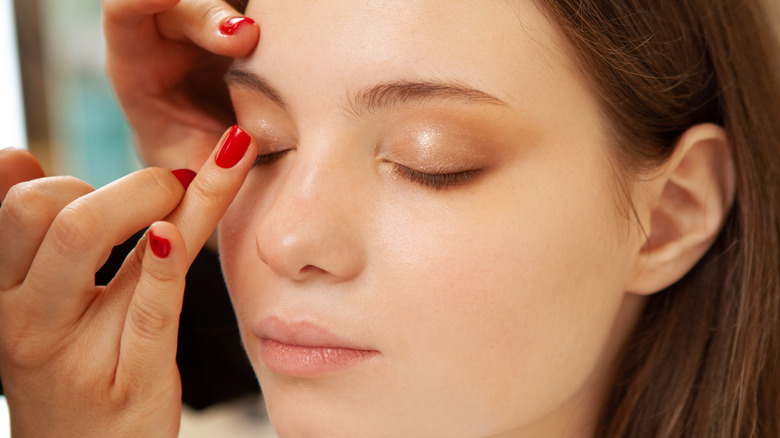 A makeup artist applying primer on a client