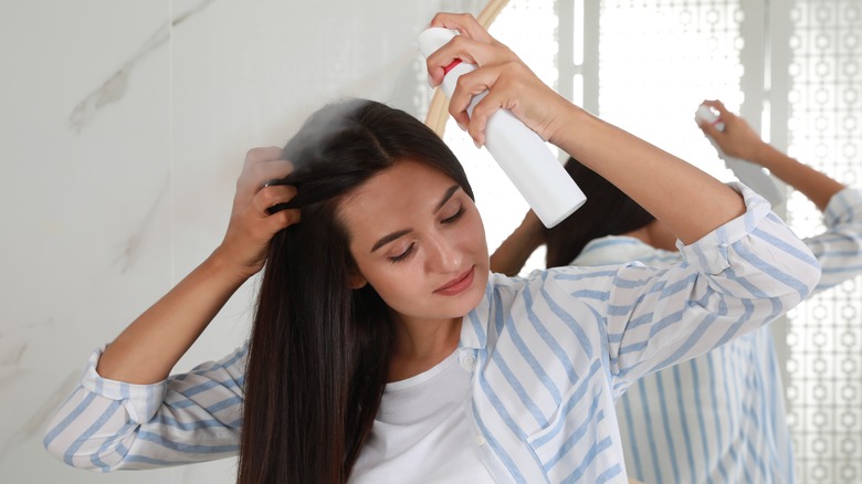 girl applying dry shampoo to hair