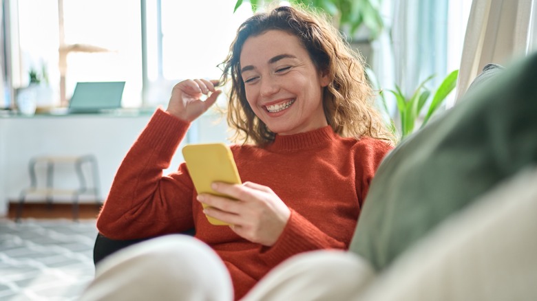 Woman smiles at phone screen