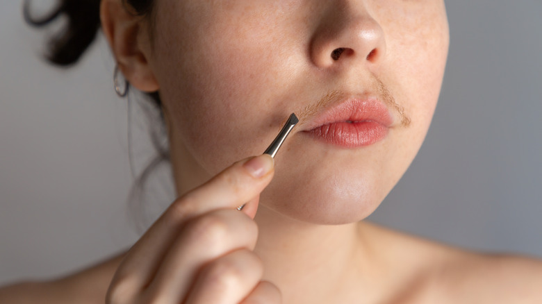 Woman plucks moustache