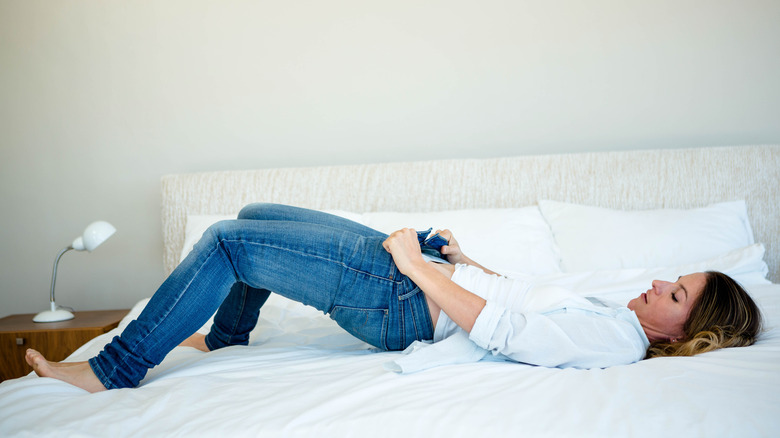 Women putting jeans on bed