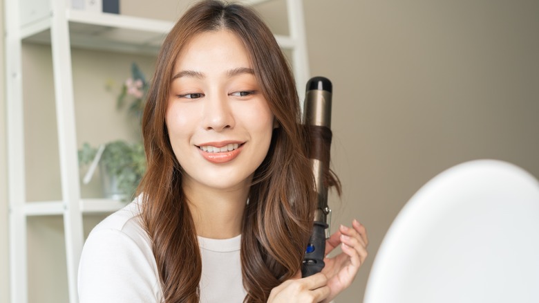 Woman curling hair with ceramic curling iron